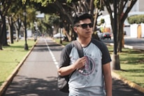 A happy customer wearing a tshirt design while walking in a sunny park.