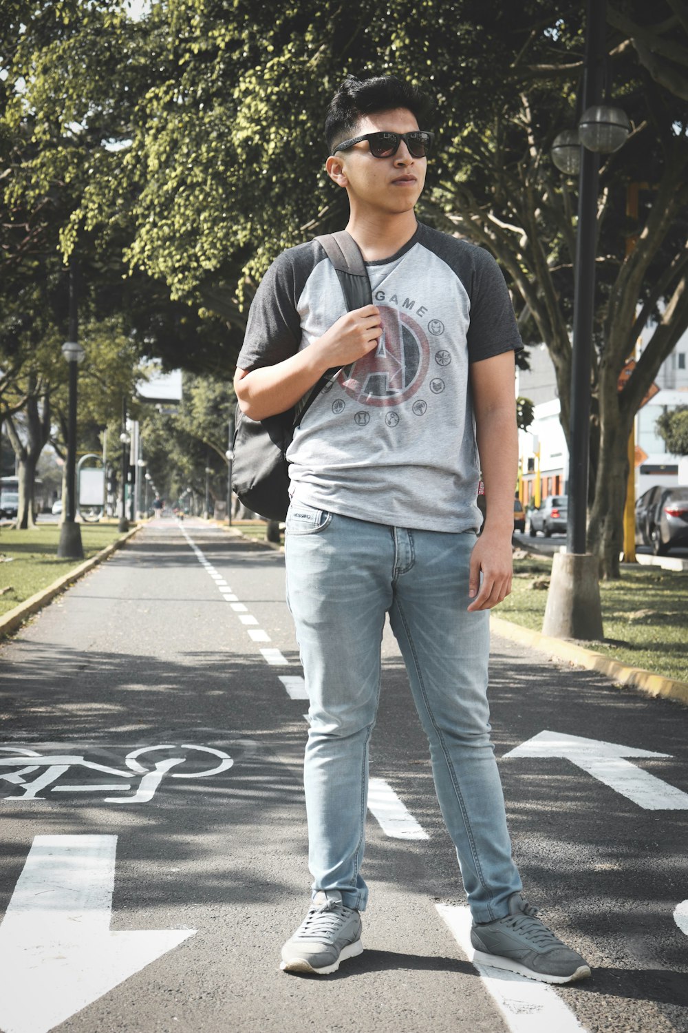 man standing on concrete road near trees