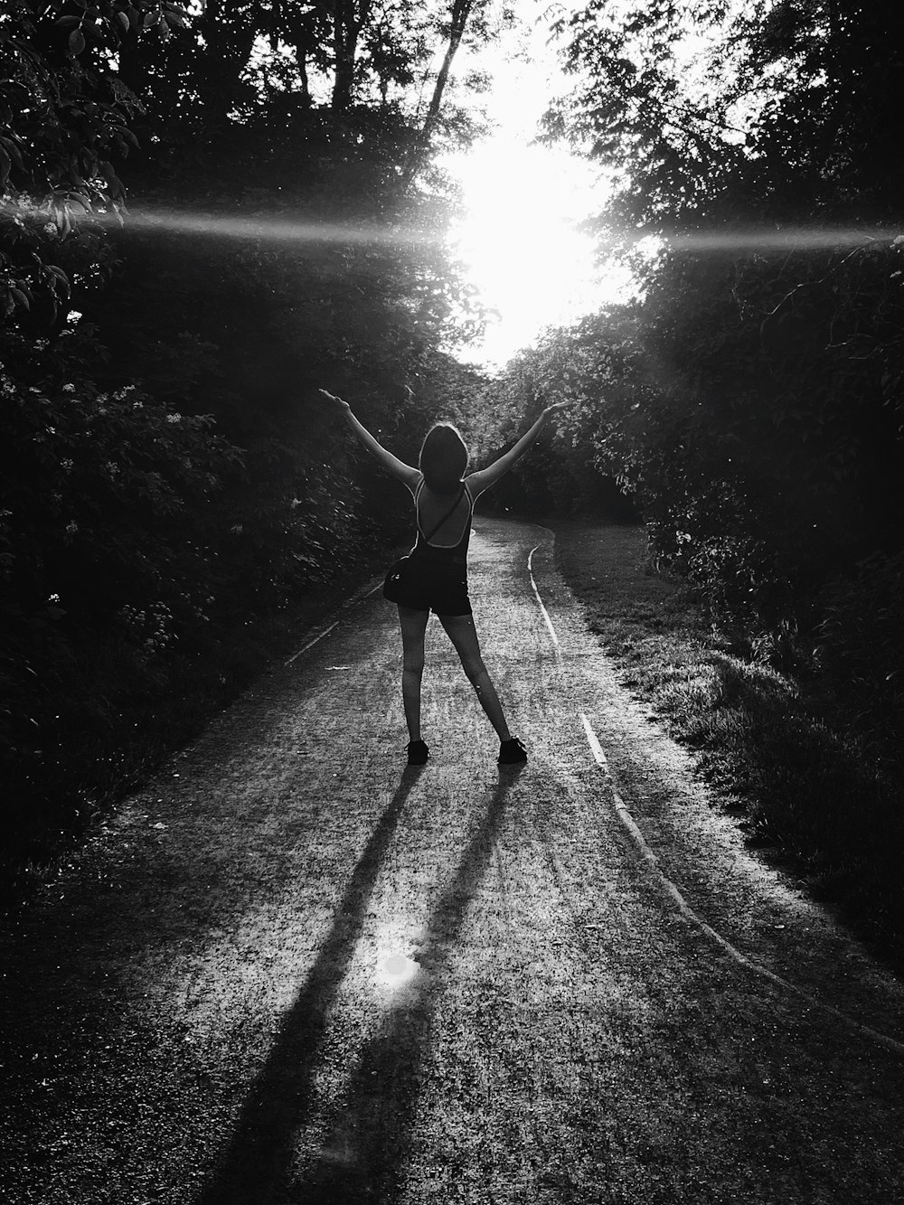 woman standing near road while raising her both hands