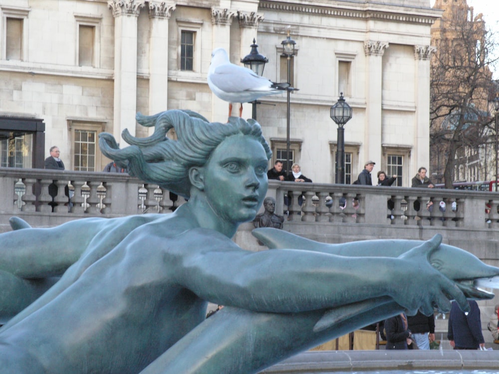 woman holding gray dolphin statue