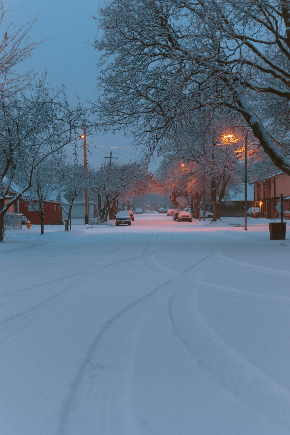 a snow covered street with cars parked on the side of it