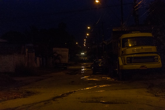 A tow truck assisting a car on a quiet road at dusk with a warm, reassuring light.