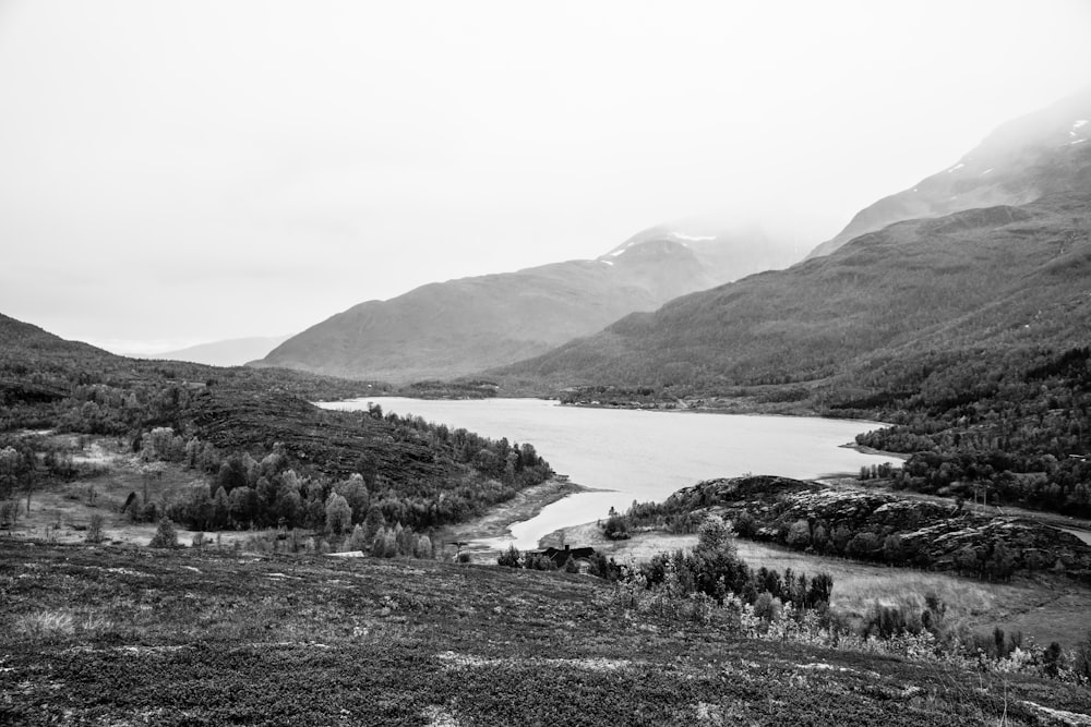 grayscale photo of lake between hills