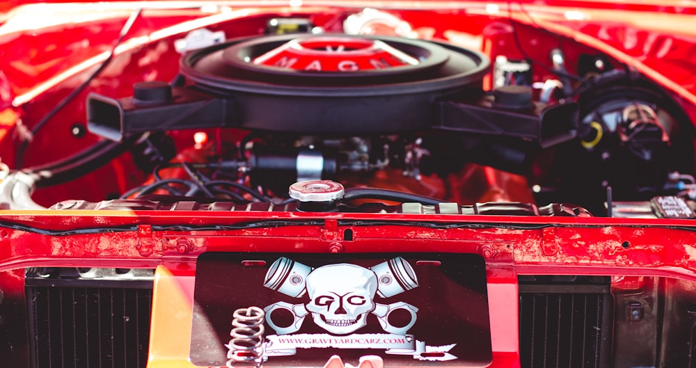the engine compartment of a red car with a skull on it