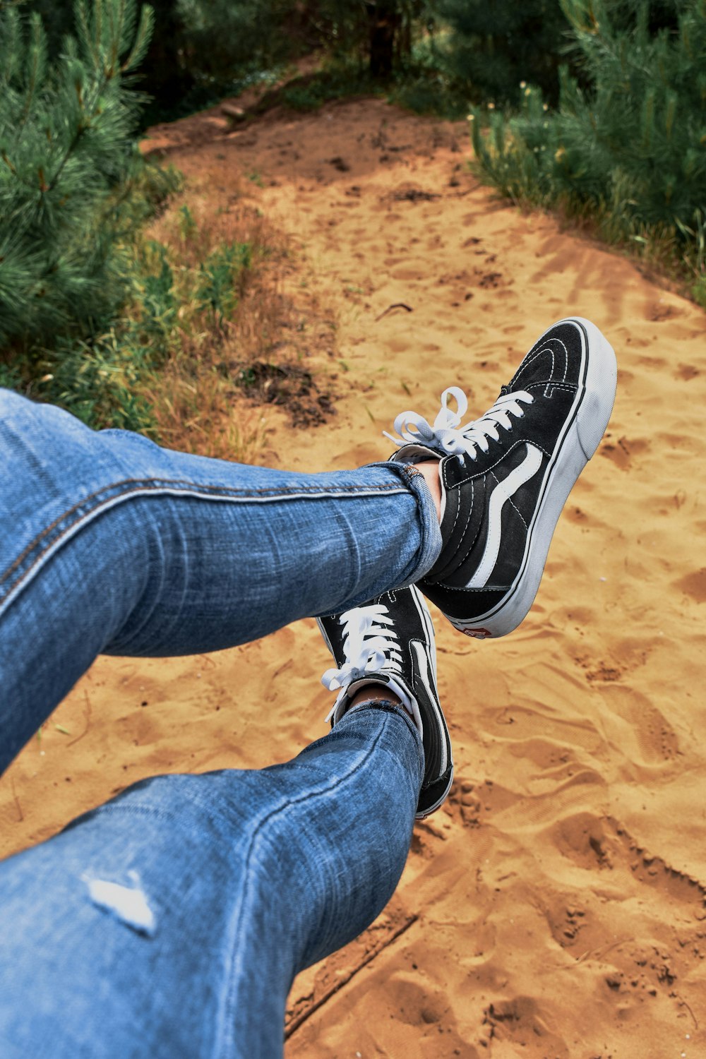 a person sitting on a bench with their feet in the sand