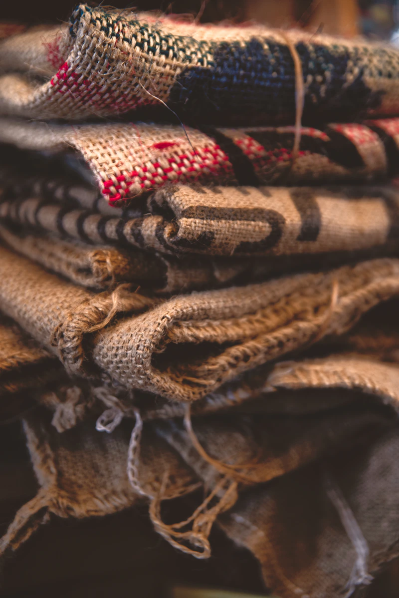 Folded burlap and canvas bags stacked on a rustic wooden shelf
