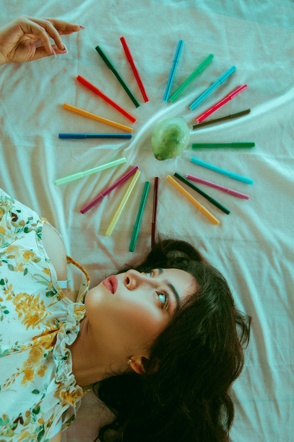 woman lying beside colored pens