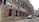 A long, red-brick industrial building with a painted sign 'IMPERIAL PAPER BOX CO.' along its side. The building features numerous black-framed windows and is set in an alleyway with parked vehicles, including a white van and a car.