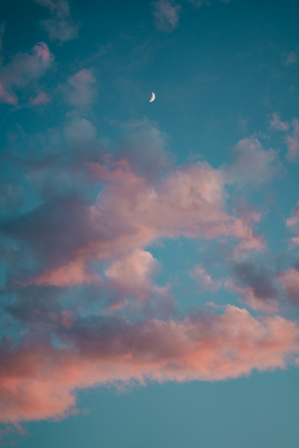 a pink and blue sky with a half moon