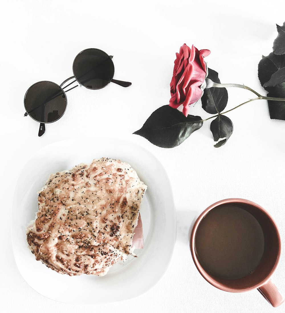 a white plate topped with a piece of cake next to a cup of coffee