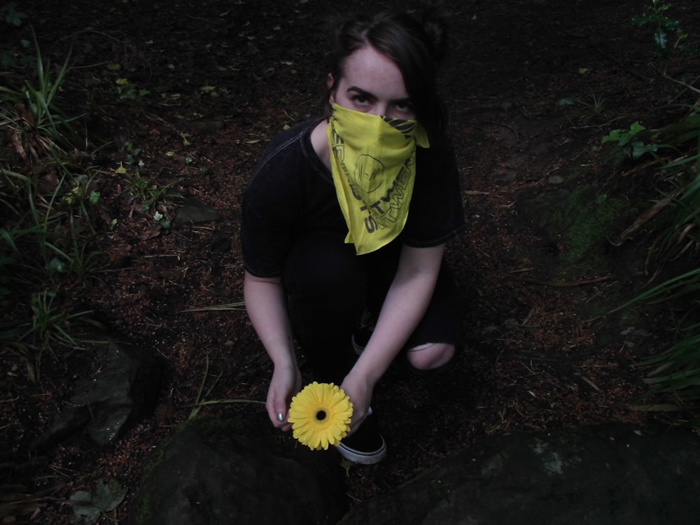 unknown person holding yellow flower outdoors