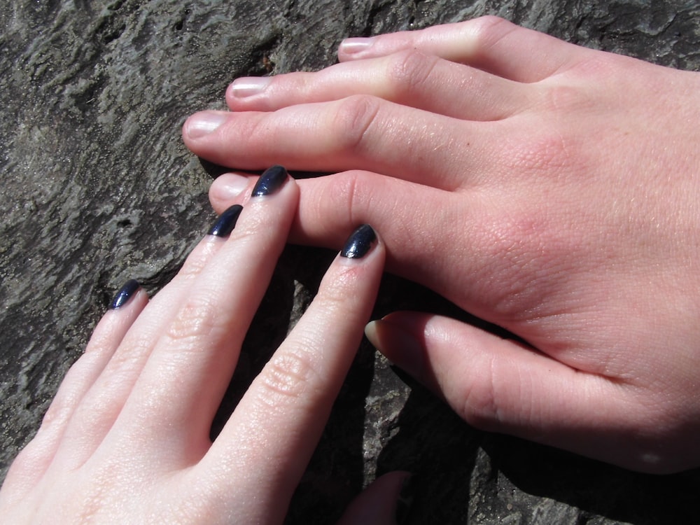 two hands holding each other on a rock