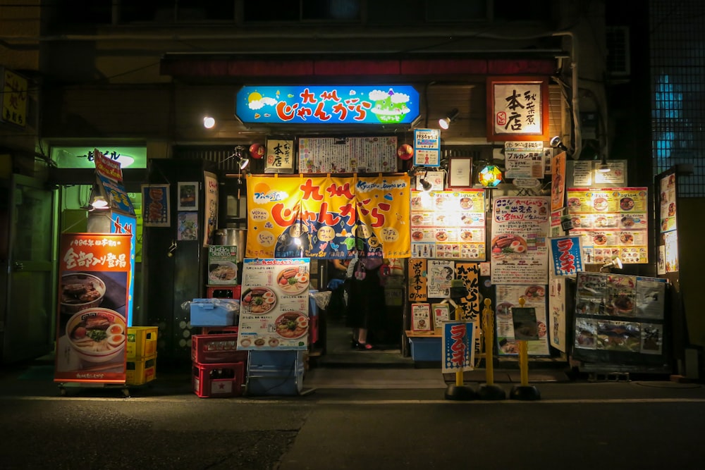 a store front at night with a woman standing in front of it