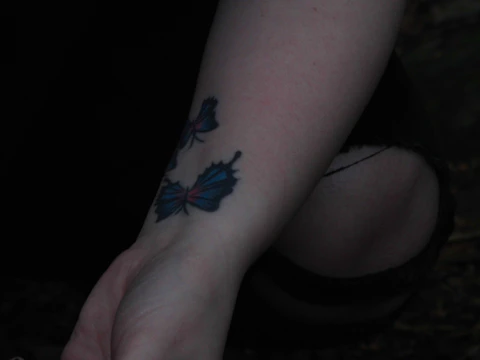 Close-up of a cyberpunk style scar camouflage tattoo on forearm with neon blue highlights.