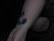 Close-up of a delicate fine-line tattoo on a forearm with soft natural lighting.