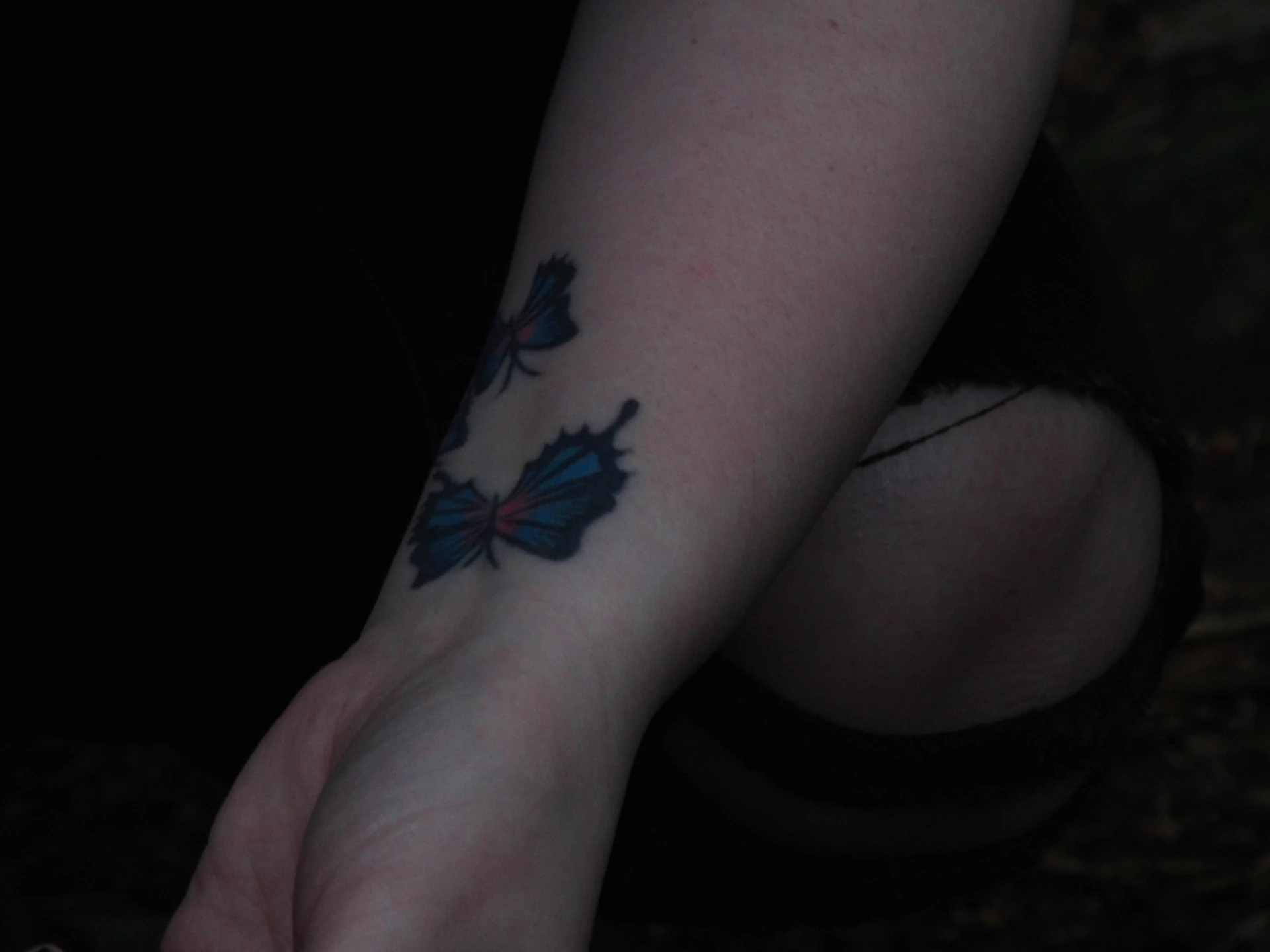 Close-up of a detailed black and grey tattoo on a forearm with soft natural lighting