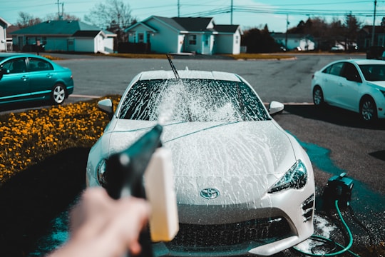 person spraying water on vehicle