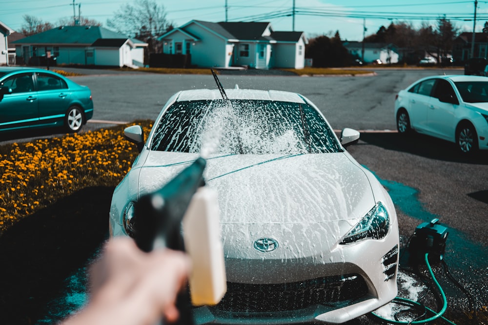 person spraying water on vehicle