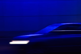 A motion-blurred image of a vehicle moving at high speed with a distinct blue hue. The background is composed of horizontal lines, creating a dynamic and futuristic atmosphere.
