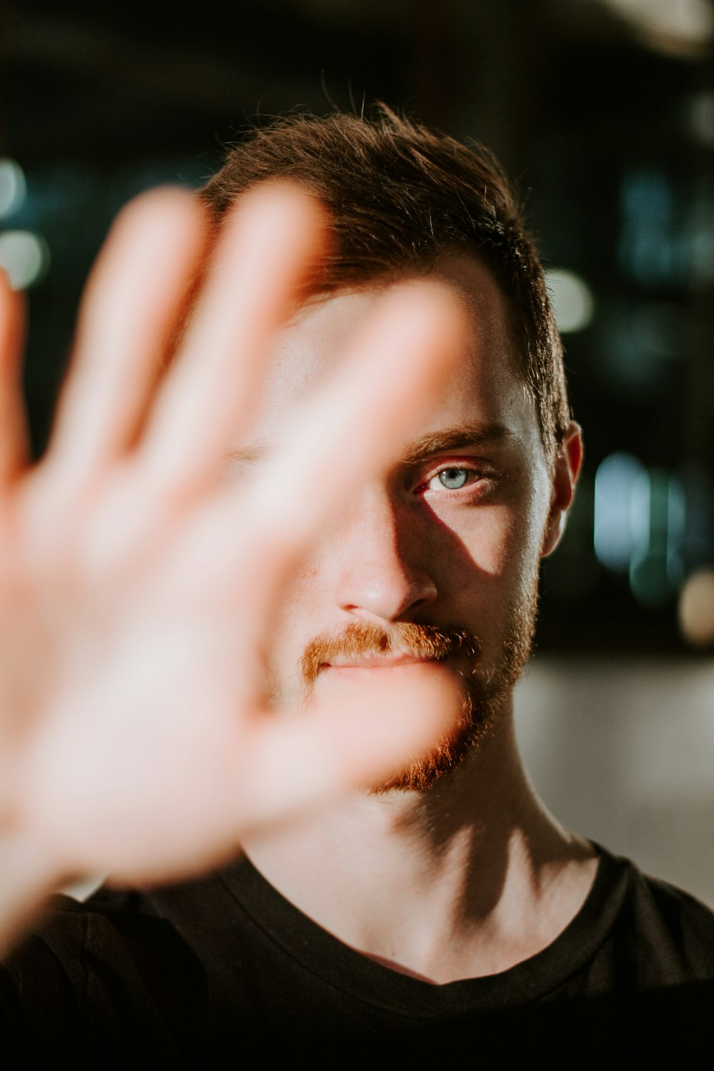 shallow focus photo of man in black crew-neck shirt showing his right hand