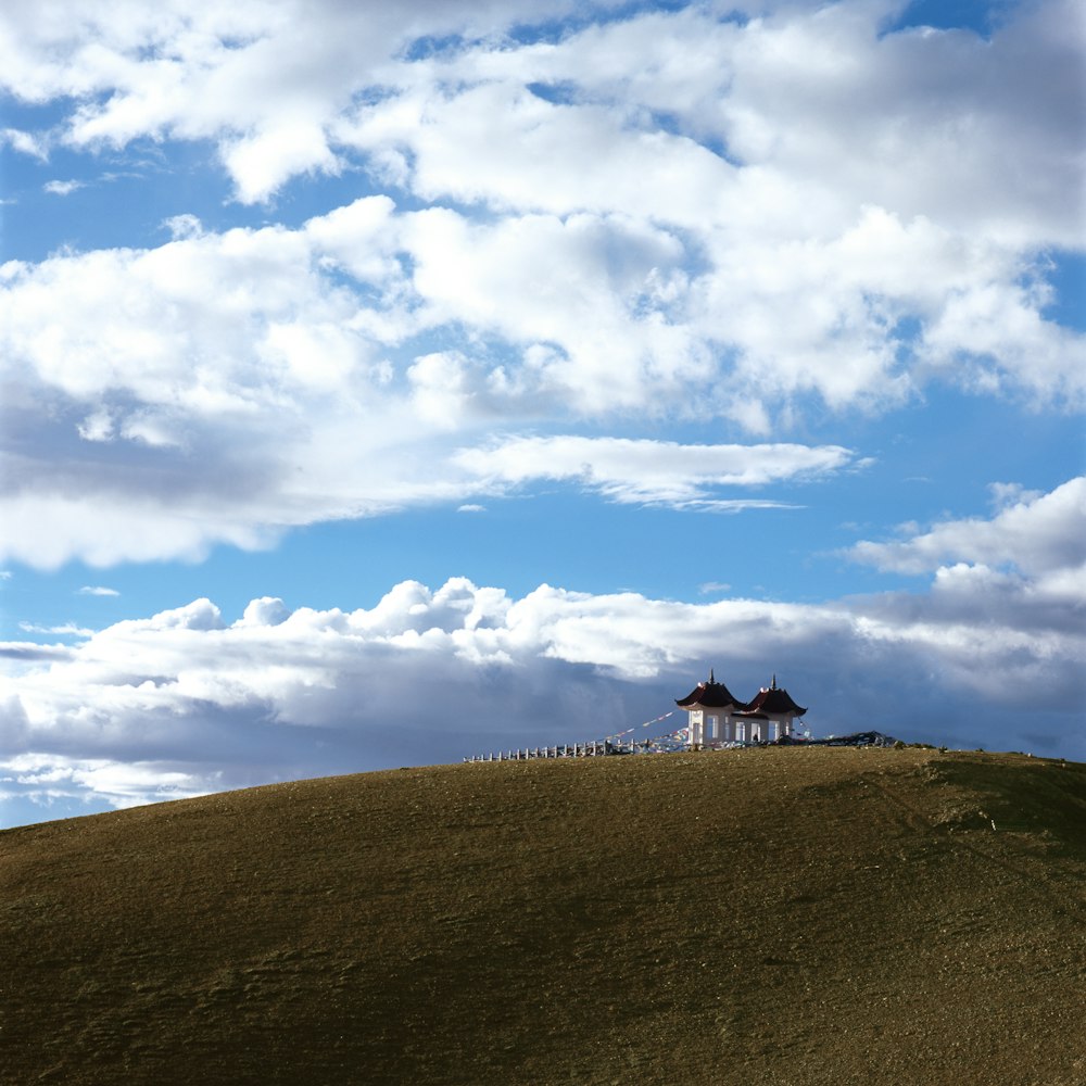 Casa de madera blanca y negra en campo verde bajo cielos blancos y azules