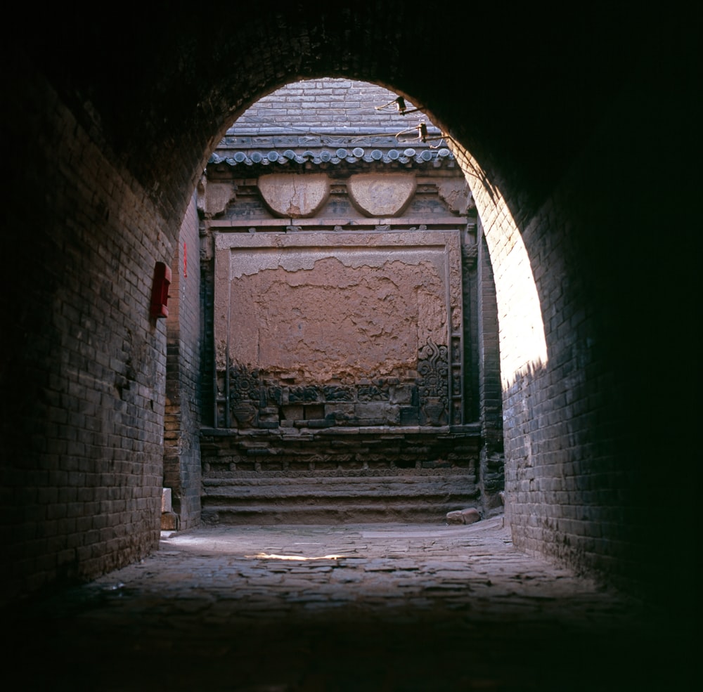 a tunnel leading to a building with a clock on the wall