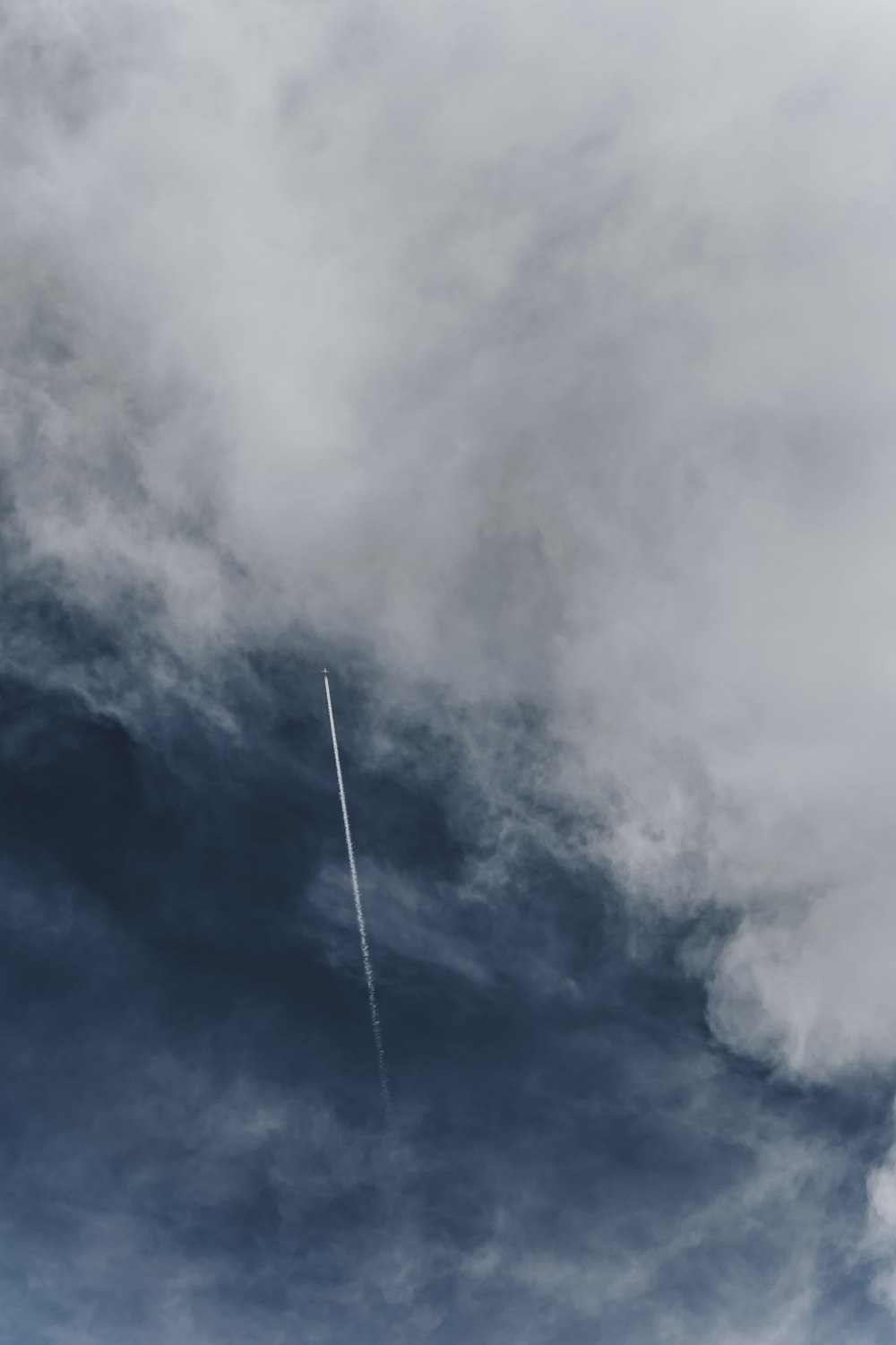 a plane flying through a cloudy blue sky