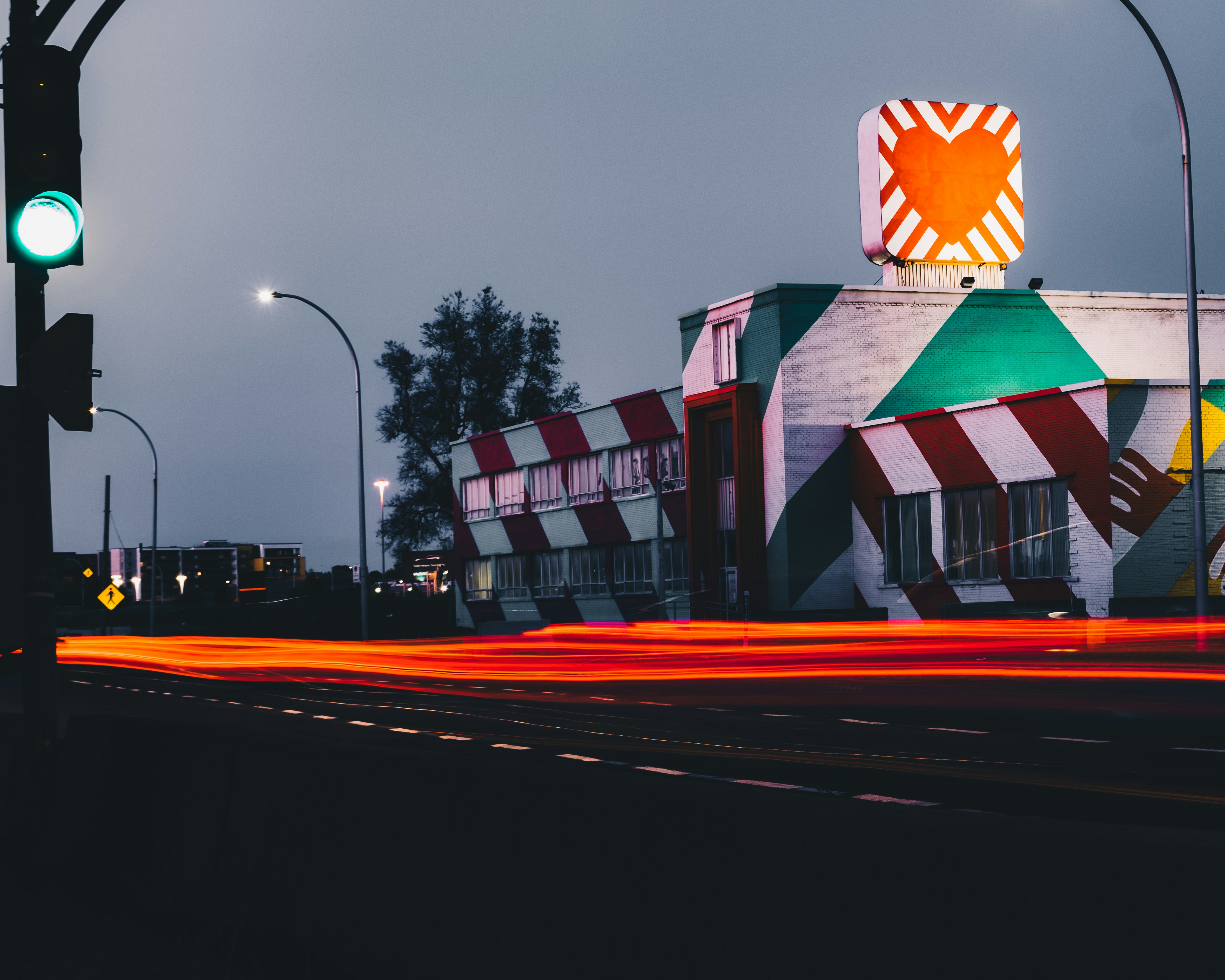 time-lapse photography of vehicle passing white and red concrete building with red and white heart board