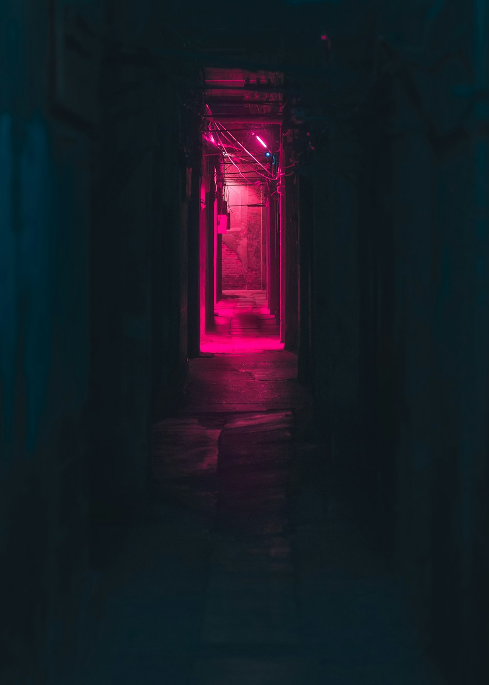 a dark hallway with a red light at the end