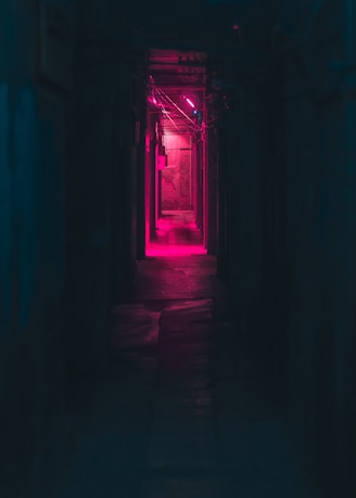 a dark hallway with a red light at the end
