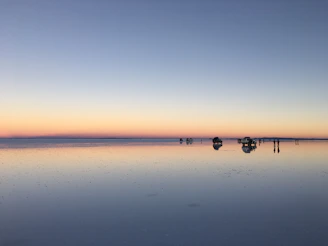 Sunset over the endless reflective salt flats with tourists taking photos