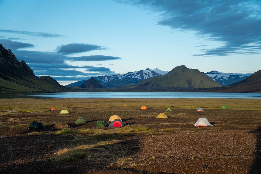 a group of tents set up in a field with mountains in the background