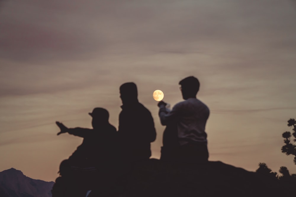 silhouette of men under moon