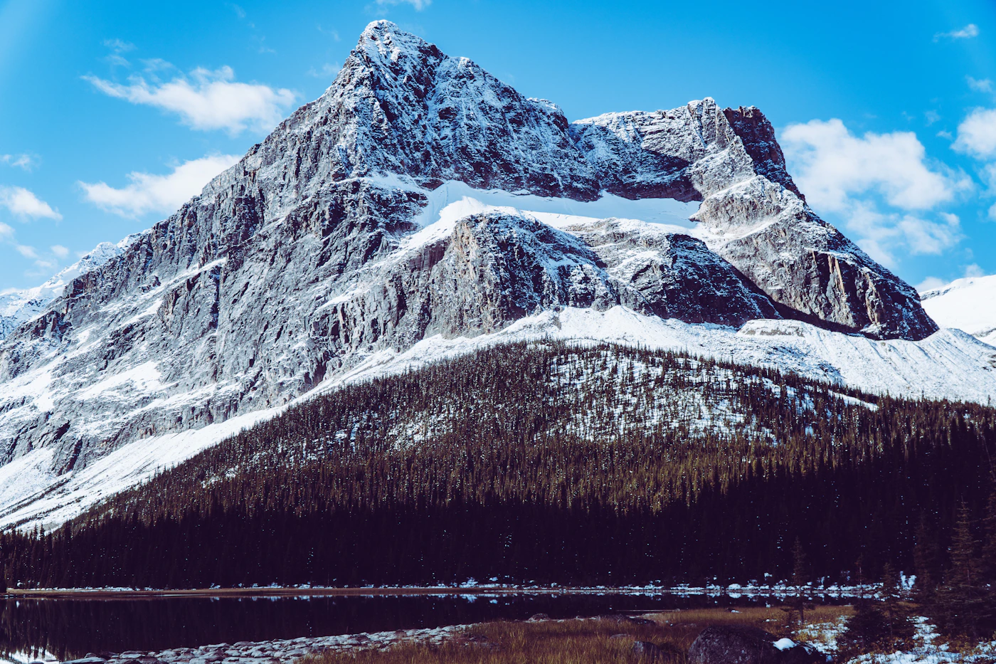 A snow-covered mountain in Jasper National Park reflected in a still alpine lake in the foreground