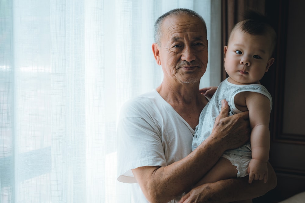 man carrying baby wearing white shirt