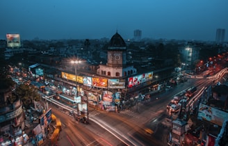 Wide shot of a busy traffic intersection featuring multiple illuminated advertising panels at dusk.
