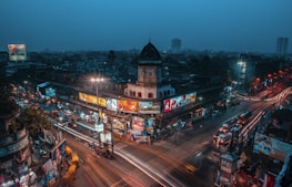 A panoramic view of a busy intersection framed by towering advertising screens illuminated at dusk.