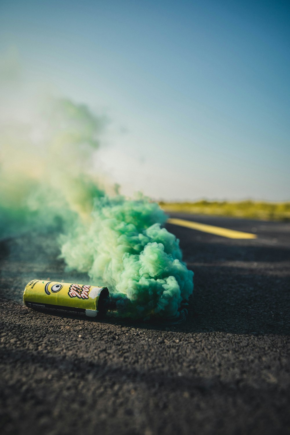 green bottle with smoke on concrete road during daytime