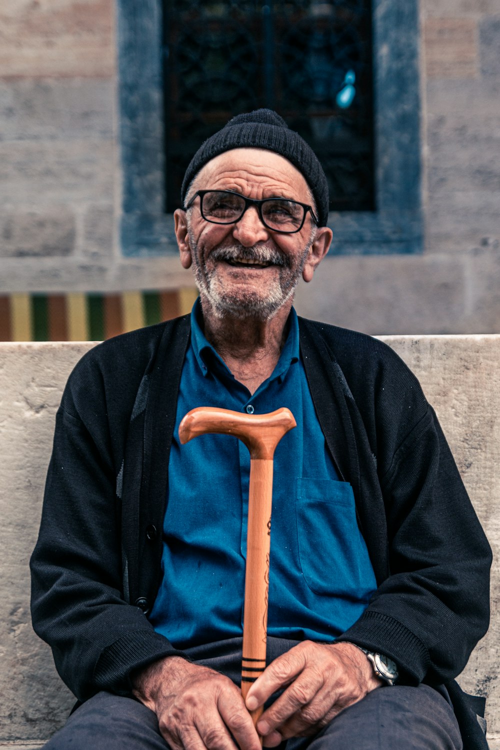 hombre sonriente sentado en el banco sosteniendo un bastón