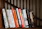 A collection of vibrant non-fiction books arranged on a wooden shelf.