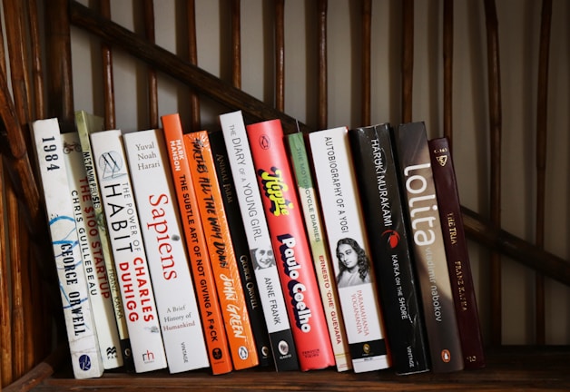 A collection of various books on a wooden shelf.