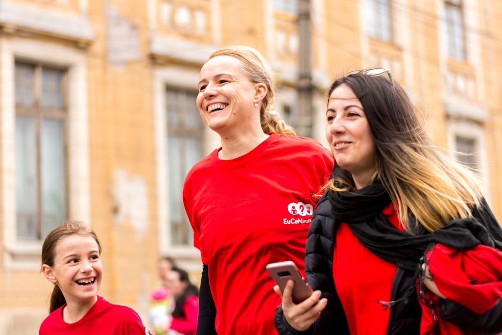 smiling woman between girl while walking near building