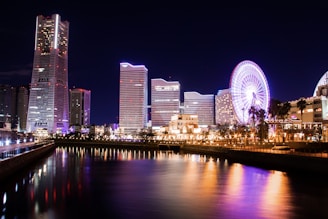 lighted city buildings near body of water at night