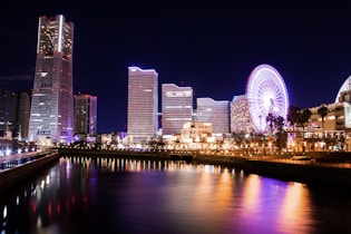 lighted city buildings near body of water at night