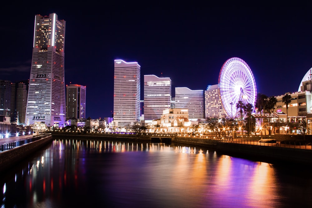 lighted city buildings near body of water at night