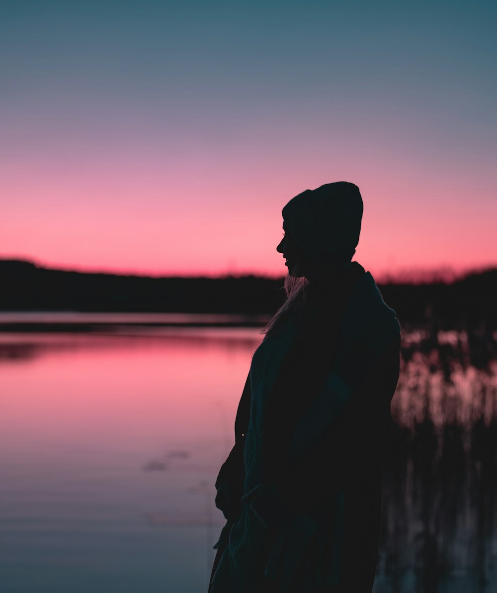silhouette photography of person standing near body of water