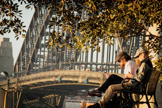 Two teenagers sitting on a park bench, animatedly discussing a story they just read on their phones.