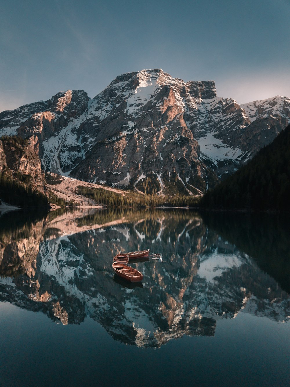 empty boats on body of water near glacier mountains