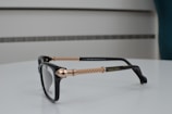 Close-up of sleek black and gold eyeglasses on a white surface.