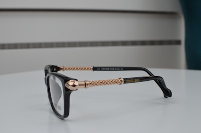 Close-up of sleek black and gold eyeglasses on a white surface.